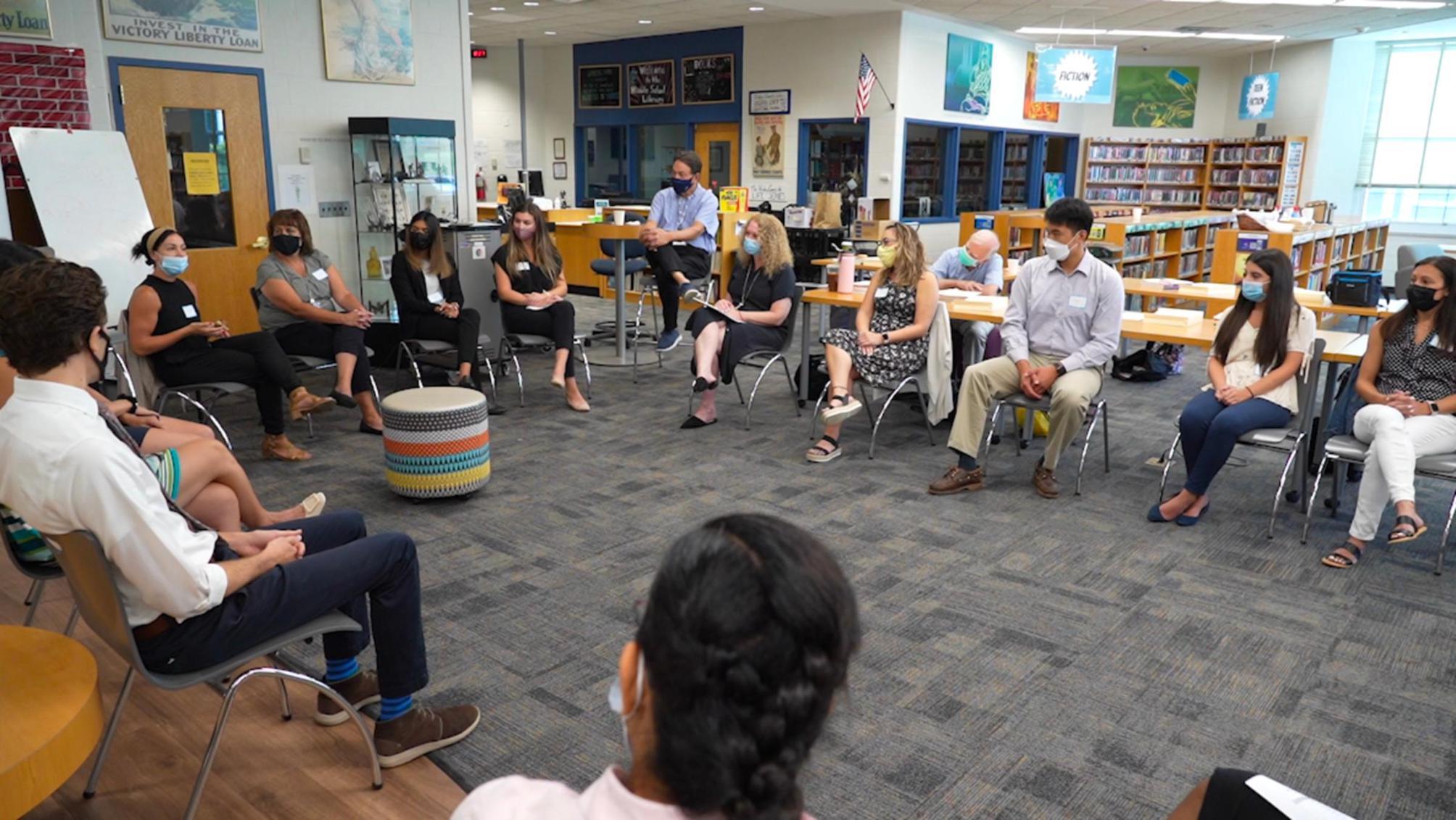 Teachers and students sit in the library